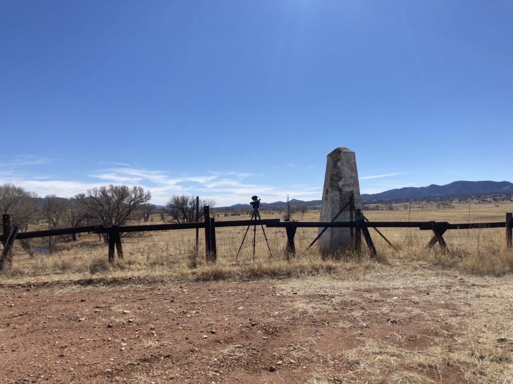 An old concrete pillar, about 8 feet high. In front of it is a low barrier made of angle iron.